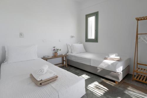 a white room with two beds and a mirror at Tzitziki in Piso Livadi