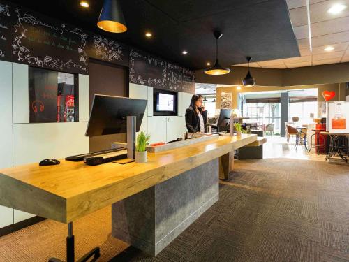 a woman standing at a counter in a restaurant at ibis Bordeaux Pessac Route des Vins in Pessac