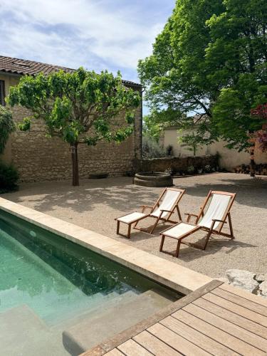 two chairs sitting next to a swimming pool at La Brèche - Mansion with swimming pool in Velleron
