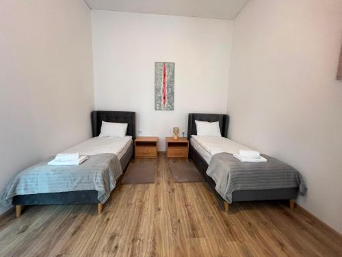 two beds in a room with wooden floors at Ebram Apartments Görlitz in Görlitz
