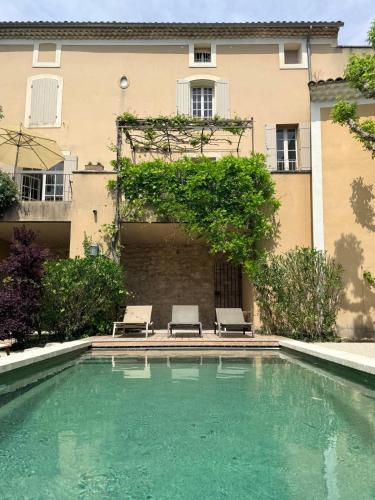 a swimming pool with two chairs and a building at La Brèche - Mansion with swimming pool in Velleron