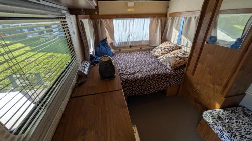 a small room with a bed and a window in an rv at Caravane Cosy - 5min Circuit 24h du Mans in Changé
