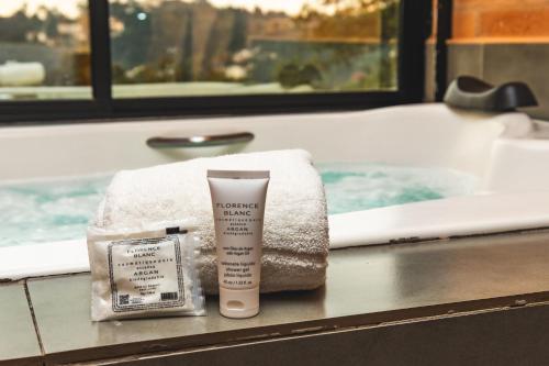 a pile of towels and a bottle of sunscreen next to a bath tub at DOM Hotel in Campos do Jordão