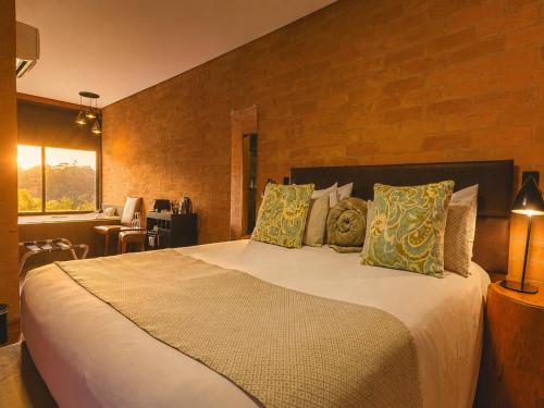 a bedroom with a large bed with pillows at DOM Hotel in Campos do Jordão