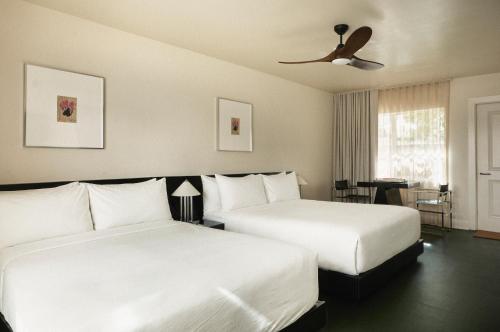 a hotel room with two beds and a ceiling fan at Perroquet Hotel in Fort Lauderdale