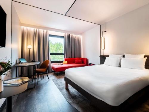 a hotel room with a large bed and a red couch at Novotel Atria Nimes Centre in Nîmes