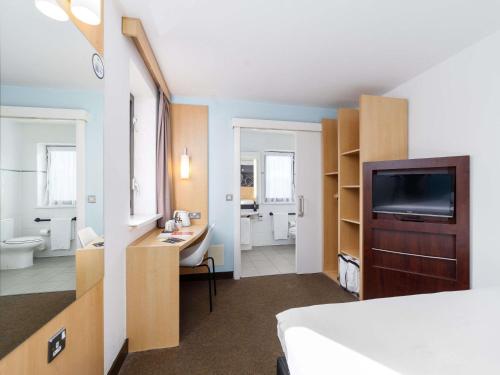 a hotel room with a bed and a television and a bathroom at ibis Southampton in Southampton