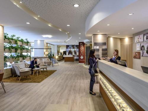 two women standing at a counter in a hotel lobby at Novotel Frankfurt City in Frankfurt