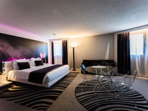 a bedroom with a large bed and a table at Novotel Orléans Saint Jean de Braye in Saint-Jean-de-Braye