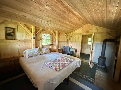 a bed in a room with a wooden ceiling at Lookout Cabin in Barton
