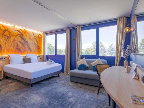 a bedroom with a bed and a couch and a table at Mercure Lyon Est Villefontaine in Villefontaine