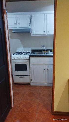 a kitchen with a stove and a sink and white cabinets at Cómodo departamento equipado in Chihuahua