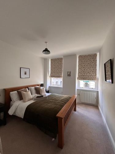 a bedroom with a large bed and two windows at The Linen Loft - 2 Bed Apartment - Central Town Location - Reserved Parking Space Included in Ross on Wye