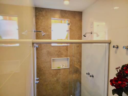 a bathroom with a shower with a glass door at Villa Pella - Chalé Cravo- café da manhã in Brumadinho