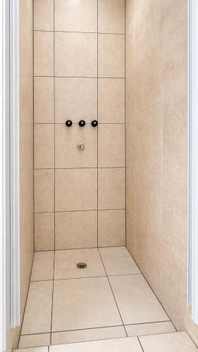 a shower with a glass door and a tile floor at Tu Hostel Tucuman in San Miguel de Tucumán