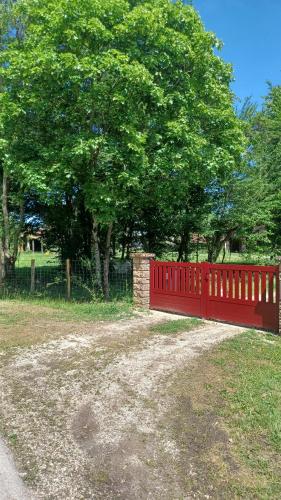 a red fence in a field next to a tree at Le Gîte du Vauvril in Saint-Usuge