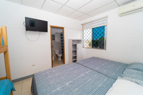 a bedroom with a bed and a tv on the wall at Pargo, habitación privada de Flor de Lis Beach House in Playas