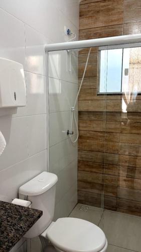 a bathroom with a toilet and a glass shower at Recanto Tarobá in Ponta Grossa