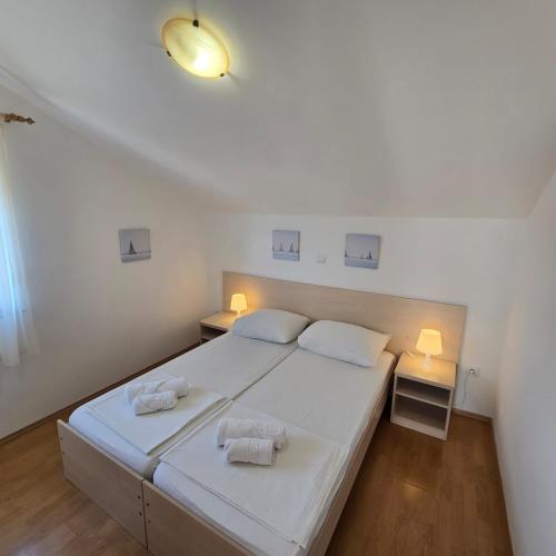 a bedroom with a large white bed with two towels at Pansion Bonaca in Srima