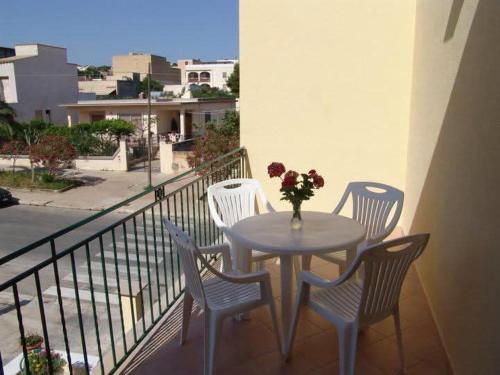 a table with chairs and a vase of flowers on a balcony at Abbadia in San Vito lo Capo