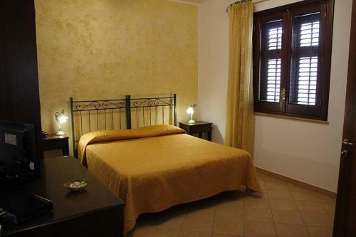 a bedroom with a bed and a window at Abbadia in San Vito lo Capo