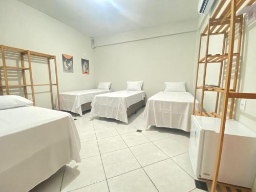 a room with two beds with white sheets at Pousada Âncora - 14 Suítes completas com Ar, TV, Frigobar e Wi-Fi, para grupos ou viajantes individuais. in Gravataí