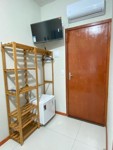 a room with a door and a tv and a microwave at Pousada Âncora - 14 Suítes completas com Ar, TV, Frigobar e Wi-Fi, para grupos ou viajantes individuais. in Gravataí