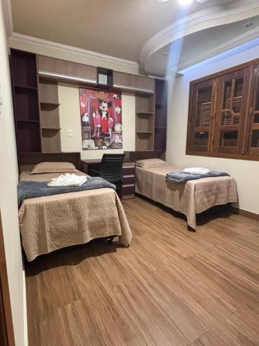 a bedroom with two beds and a wooden floor at Dara House apart e eventos com piscina, sauna, Jacuzzi e área gourmet para festas in Cachoeira do Campo