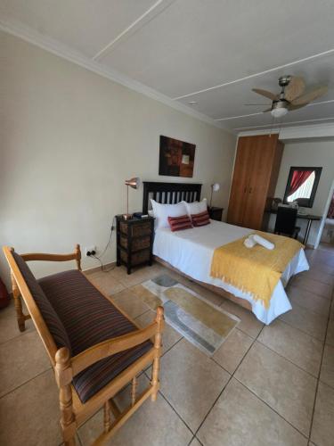 a bedroom with a bed and a chair at Swasti Guesthouse in Boksburg