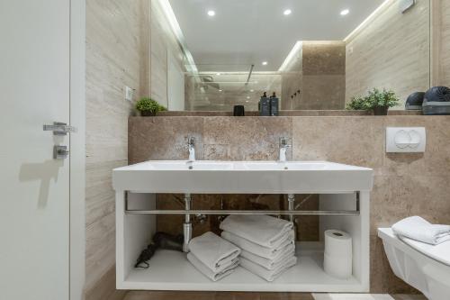 a bathroom with a sink and a pile of towels at Shell Sky Luxury Penthouse with Private Pool in Zadar