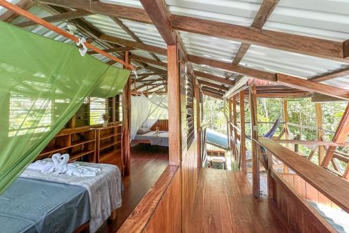 a bedroom with a bed in a room with wooden floors at Casa Aire Libre - Jungle immersion - Natural pool - Waterfall in Puerto Jiménez