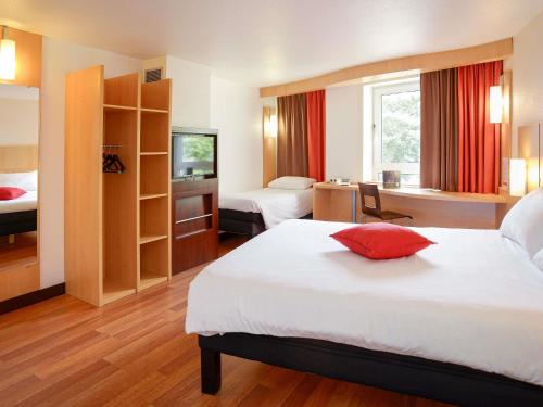 a hotel room with two beds and a red pillow at ibis Toulouse Centre in Toulouse