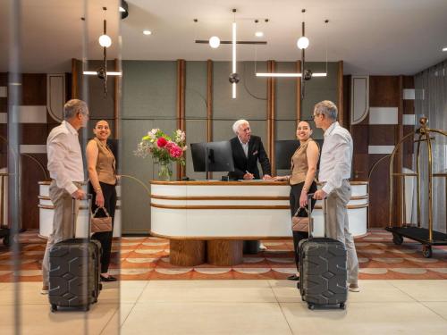 a group of people with luggage standing in front of a desk at Hotel Mercure Wien City in Vienna