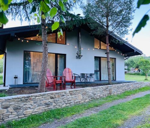 a house with a stone wall and two red chairs at Котедж RIVERHILL 2-4 осіб in Slavske