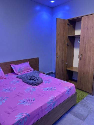 a bedroom with a purple bed with a wooden cabinet at Apartment Luxueux a Cité Apix in Niadyorane