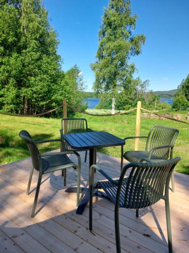 three chairs and a table on a wooden deck at Glamping Tolvsbo Inn in Söderbärke