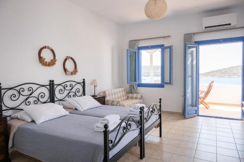 two beds in a bedroom with a view of the ocean at Studios Angela Port in Leipsoi