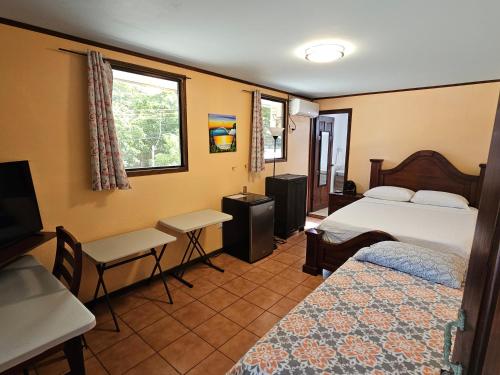 a bedroom with two beds and a table and a desk at Outback Hermosa in Playa Hermosa
