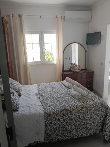 a bedroom with a bed with a dresser and a mirror at Vila les Roses Quartos Jardim e Montanha in Porches