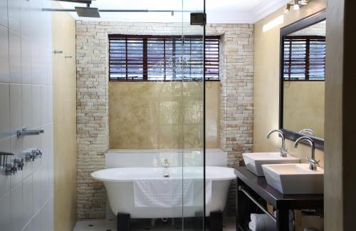 a bathroom with a tub and two sinks and a shower at Village Ridge Boutique Stays in Pretoria