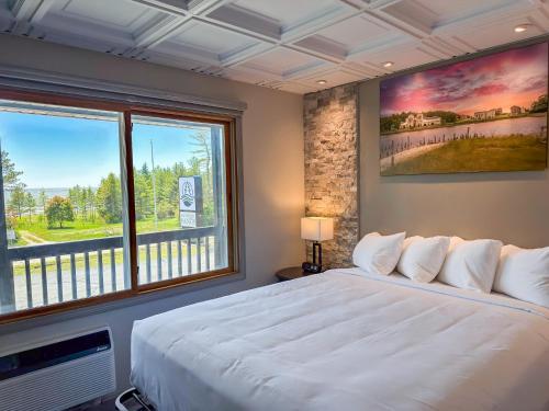 a bedroom with a large white bed and a window at Manistique Sands in Manistique