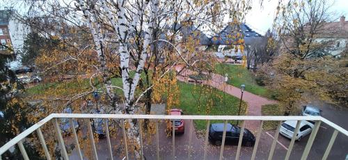 a balcony with a tree and cars parked in a parking lot at Arcanum Apartman in Makó