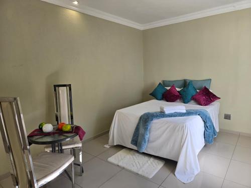 a bedroom with a bed with purple and blue pillows at Aquasaints Sandton Logde in Johannesburg
