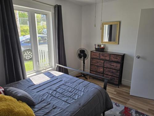 a bedroom with a bed and a window and a dresser at Le Repere, Beach, Whales, and Ferry in Saint-Siméon