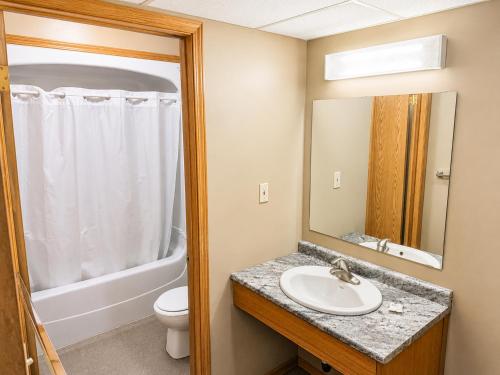 a bathroom with a sink and a toilet and a mirror at Ste Anne Hotel in Sainte Anne-des-Chênes
