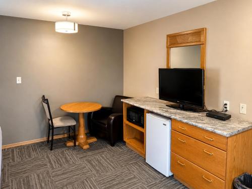 a hotel room with a desk with a tv and a table at Ste Anne Hotel in Sainte Anne-des-Chênes