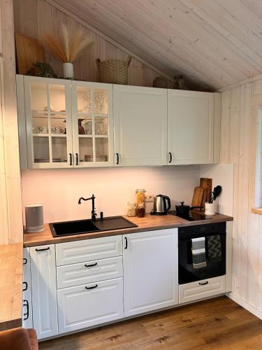 a kitchen with white cabinets and a sink at Escape to Nature - Piparmētras in Mērsrags