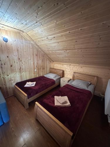 two beds in a room with wooden walls at Kesane in Jut'a