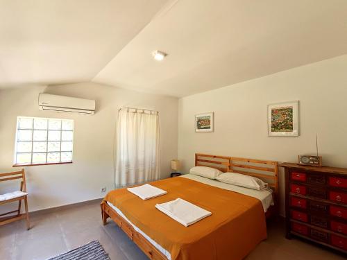 a bedroom with a large orange bed and a window at La Llar del Magraner in Barraca de Aguas Vivas