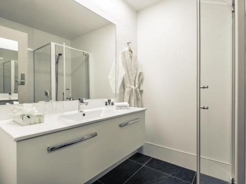 a white bathroom with a sink and a shower at Mercure Queenstown Resort in Queenstown